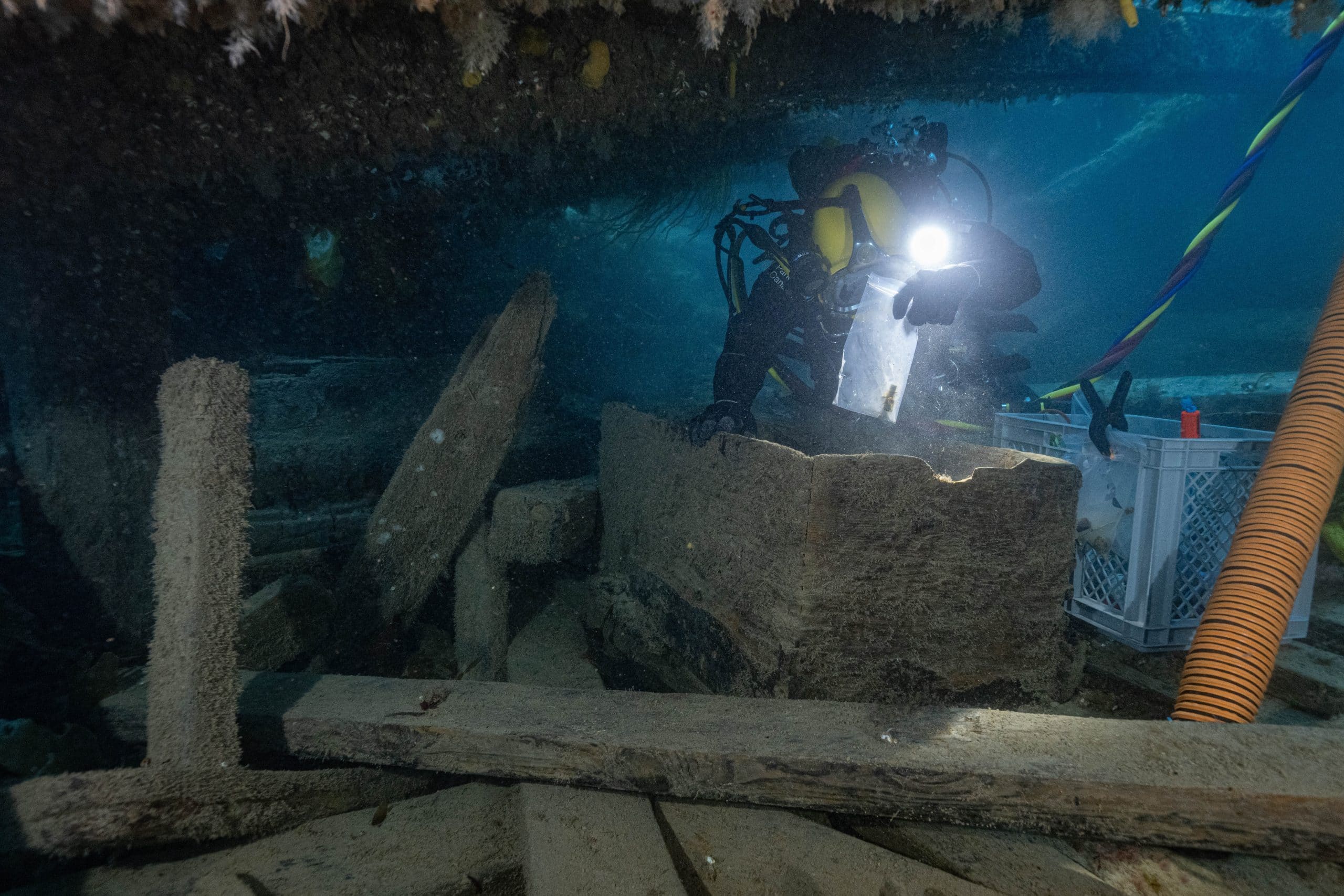 Parks Canada underwater archaeologist Marc-André Bernier carefully excavates a seamen’s chest in the forecastle (crew living quarters) on the lower deck of HMS Erebus, September 14, 2023. He holds a recovered medicinal vial in an artifact bag.