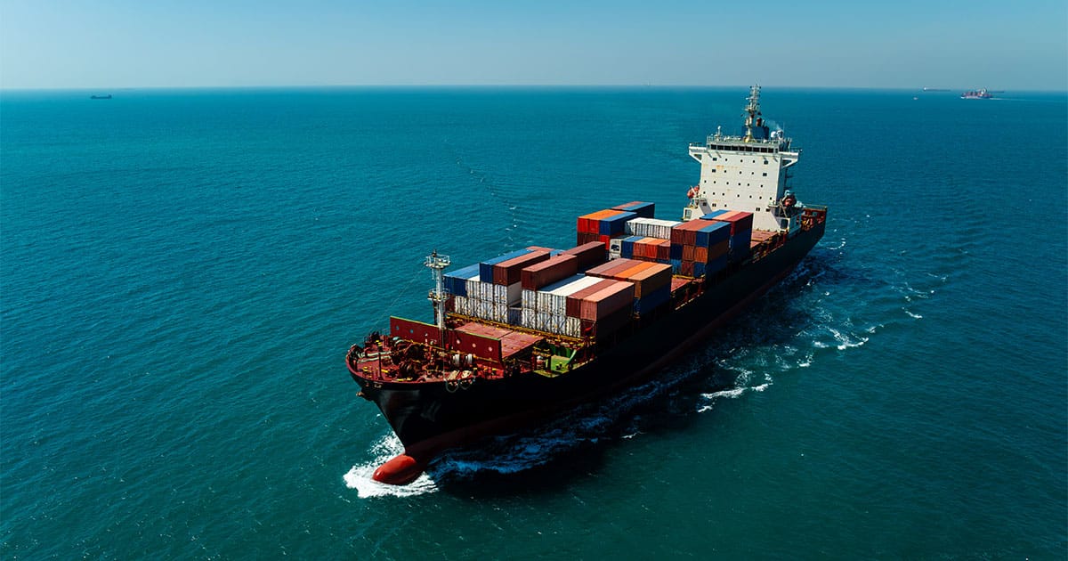 Aerial drone view of cargo ship sailing in sea. Freight transportation and global logistics.