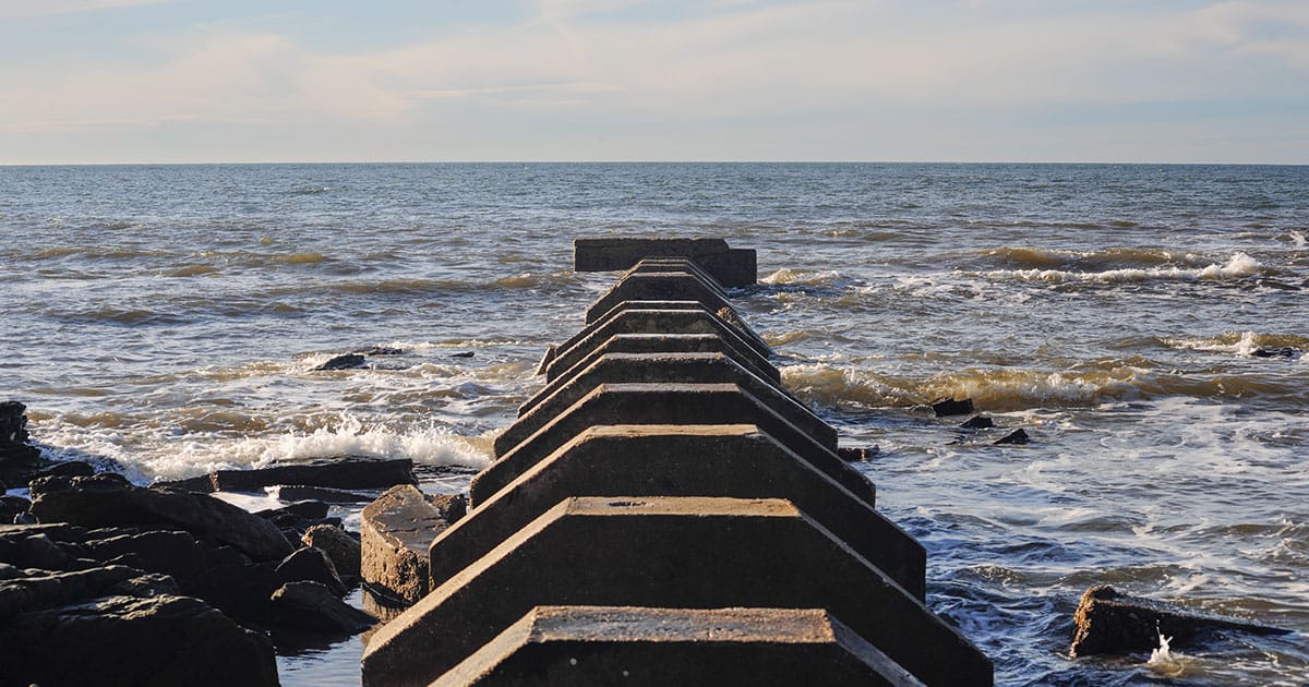 Large Concrete Stormwater Outlet Draining into the Calm Sea on a Clear Spring Day