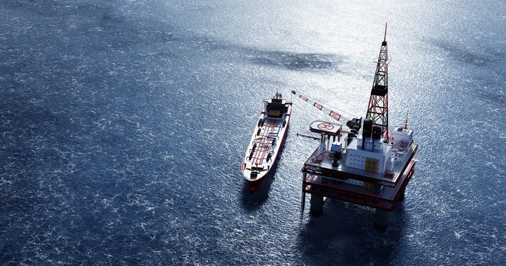 Oil platform on the ocean. Offshore drilling for gas and petroleum. Supply vessel alongside. Industrial