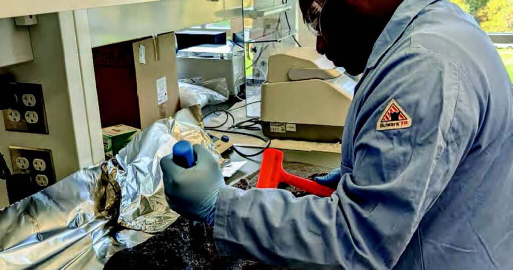 Pharmacy student Fandra Kenelak uses a hammer and chisel to find marine wood-eating shipworms in a piece of wood that was collected from the bottom of Narragansett Bay.