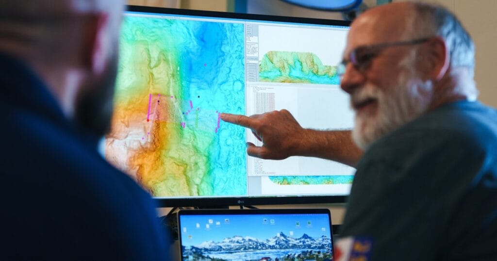 In the Computer Electronics Lab on R/V Falkor (too), Principal Investigator David Caress (Monterey Bay Aquarium Research Institute) runs through mapping mission plans with the autonomous underwater vehicle (AUV) team. The science team used shipboard sonar to map the region, followed by The Childlike Empress AUV to generate high-resolution maps and collect environmental data in the target area. These maps allowed scientists to pinpoint precise coordinates for ROV SuBastian deployment, leading to the discovery of two new active hydrothermal vent fields in record time. (Image credit: Alex Ingle, Schmidt Ocean Institute)