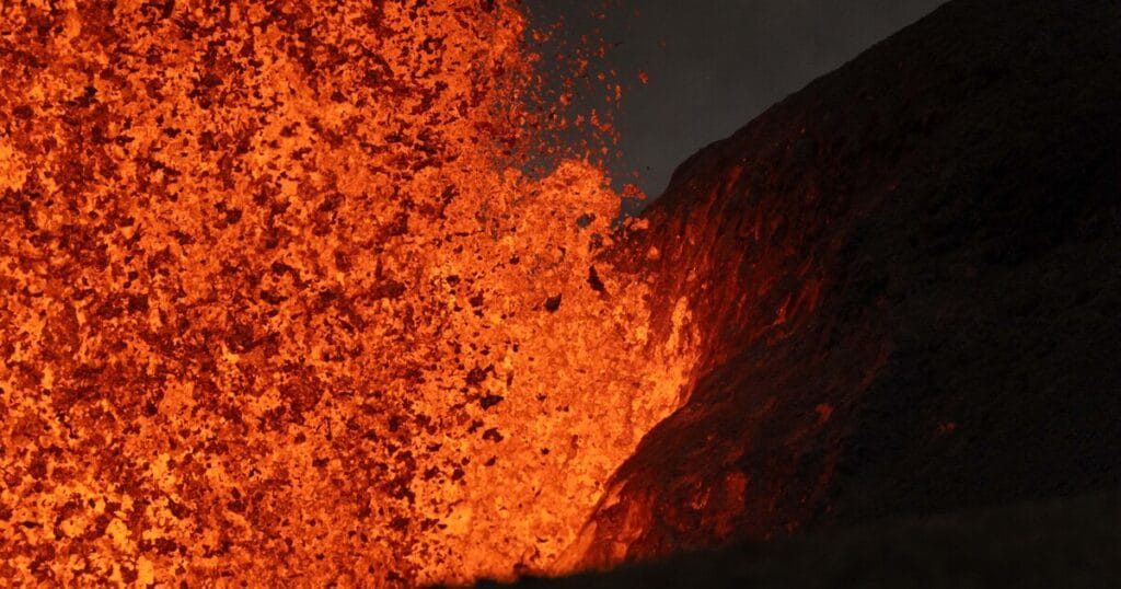 Telephoto view of the north vent lava fountain during episode 49 on June 14, 2026, showing the incandescent lava landing on and illuminating the Halema'uma'u crater wall. (Image credit: T. Paladino)